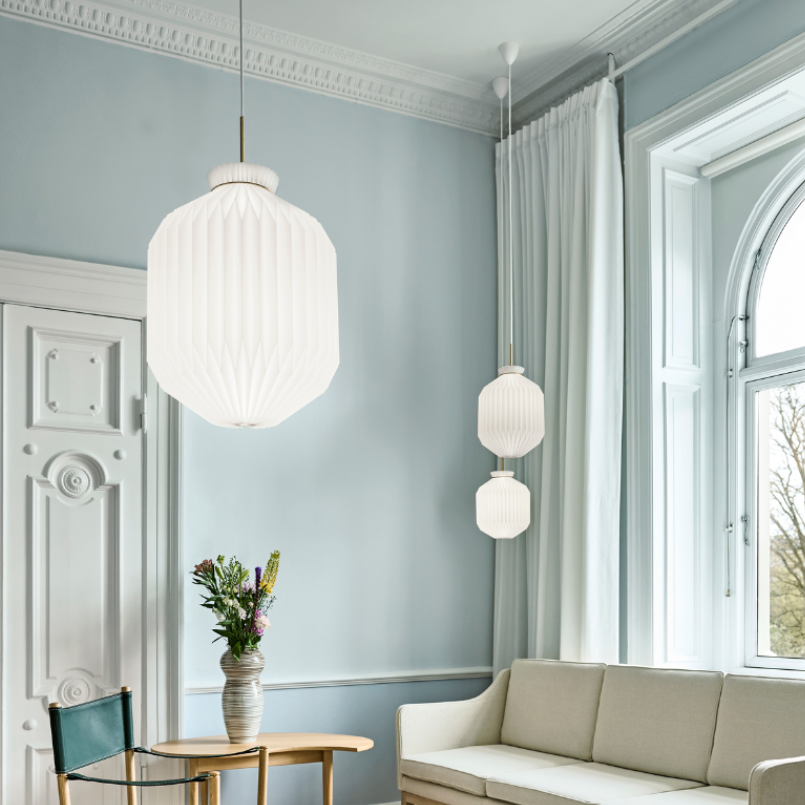 Modern living room with light blue walls, a beige sofa, and decorative lighting fixtures.